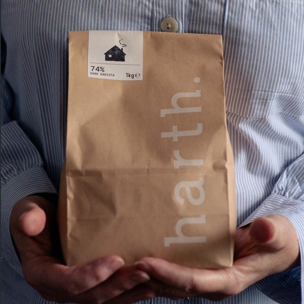 A person in a blue and white striped shirt holds a brown paper bag with the brand name 'harth.' printed vertically in white.